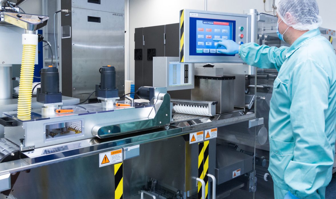Pharmaceutical technician in sterile environment working with equipment at pharmaceutical manufacturing